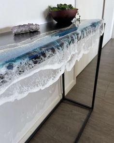 a table that has some kind of blue and white marble on it, with a plant in the background