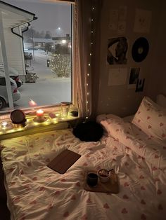 a bed with white sheets and red hearts on it, next to a window that is lit up