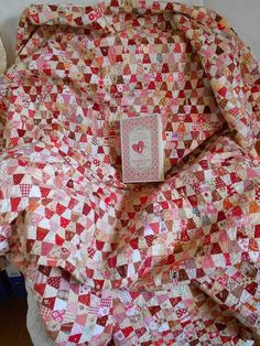 a quilt is laying on top of a chair with a book in the middle of it