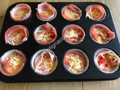 cupcakes with cheese and sauce in the middle on a black baking tray, ready to be eaten