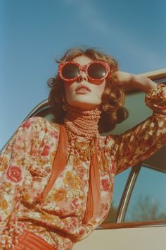 Discover the charm of vintage 70s fashion with this stunning portrait featuring a model in a retro floral dress, stylish sunglasses, and colorful necklaces. Captured with warm tones and a vibrant blue sky in the background, this Vogue-inspired editorial piece embodies the timeless elegance of the 1970s. Perfect for lovers of retro aesthetics and classic style. 70s Editorial Fashion, 70s Flash Photography, Retro Models Vintage Fashion, 1970s Fashion Photography, Vintage Look Photoshoot, 1970s Rich Aesthetic, 70s La Aesthetic, 70/80s Fashion, 70s Glam Photoshoot