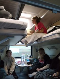 some people are sitting on bunk beds in a train or bus with drinks and water bottles