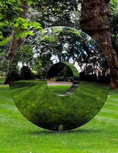 a large metal object sitting on top of a lush green field