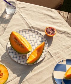 slices of melon and grapefruit sitting on a table with blue checkered plates