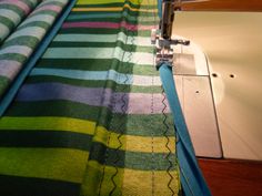 the sewing machine is working on the striped fabric that's being sewn together