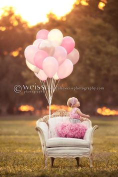 a person sitting on a couch with pink balloons in the air above their head,