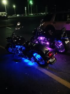 two motorcycles parked next to each other in a parking lot with blue lights on them