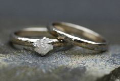 two wedding rings sitting on top of a rock with a diamond in the middle,