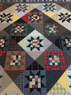 an old quilt is laying on the floor with it's squares and stars in different colors