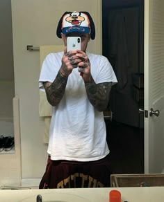 a man taking a selfie in front of a bathroom mirror wearing a football helmet