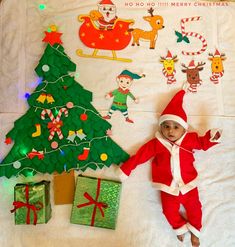 a baby dressed as santa claus next to christmas decorations