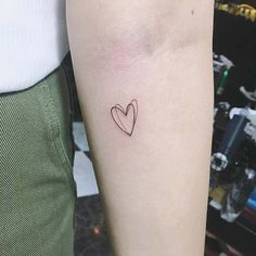 a small heart tattoo on the left inner arm, with an arrow in the middle