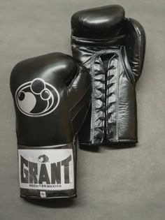 a pair of black boxing gloves sitting on top of a gray floor next to each other