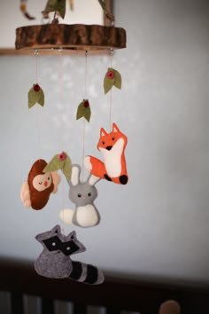 a baby crib with stuffed animals hanging from it's sides and an animal mobile in the middle