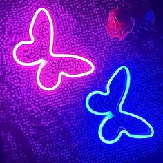 two neon signs sitting next to each other on top of a table in front of a flower