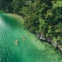 an aerial view of two people in kayaks on the water surrounded by green trees