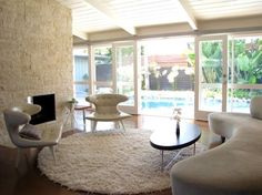 a living room filled with furniture next to a window covered in white curtains and rugs