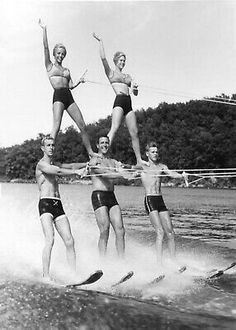 four people in bathing suits water skiing and holding onto the rope as they hold hands