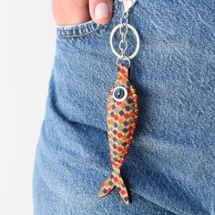 a person holding onto a fish shaped keychain with an evil eye on it