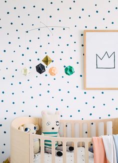 a baby's room with blue and white polka dot wallpaper, crib bedding, and artwork