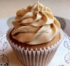 a cupcake with frosting sitting on top of a white doily covered plate