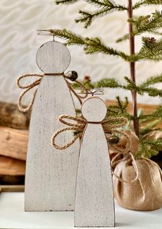 two wooden figurines sitting next to each other on top of a table near a christmas tree