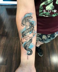 a person with a tattoo on their arm holding an anchor and snake wrapped around it