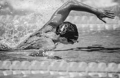 a man swimming in a pool with his arm out and head above the water's surface