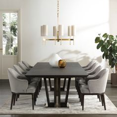 a dining room table with grey chairs and a white vase on it's centerpiece