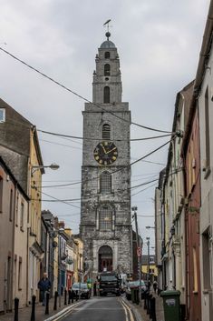 a tall tower with a clock on the side of it's face next to buildings