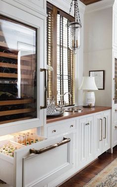 a kitchen with white cabinets and wood flooring, including a wine rack in the middle