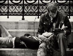 two people are sitting on a bench and one is looking at a book while the other looks down