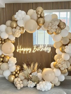 a happy birthday balloon arch with balloons and pineapples in front of a window