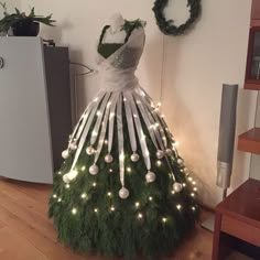 a dress made out of christmas tree branches with lights on it's bottom and sides