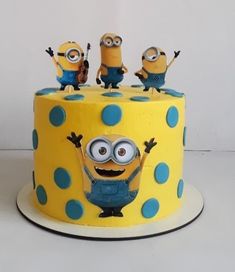 a yellow cake with blue polka dots and minion figurines sitting on top