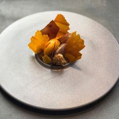 a white plate topped with food on top of a gray tablecloth covered in brown and yellow leaves