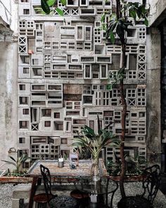 a table and chairs in front of a wall made out of wooden pallet blocks