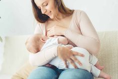 a woman sitting on a couch holding a baby