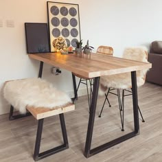 a wooden table with two chairs and a white rug on the floor next to it