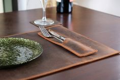 a place setting with silverware and wine glasses on a tableclothed place mat