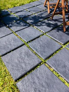 a chair sitting on top of a grass covered field next to a stone patio area