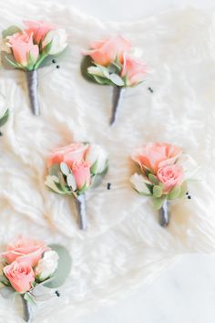 pink roses are arranged on the side of a white table cloth with green leaves and flowers