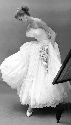 a black and white photo of a woman in a dress with flowers on the skirt