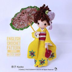 a crocheted doll holding an umbrella and wearing a yellow dress with flowers on it