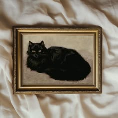 a painting of a black cat laying on a white sheet with gold trim around it's edges