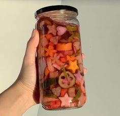 a person holding a jar full of cut up vegetables