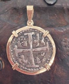 a gold and silver pendant with an image of a cross on it's side