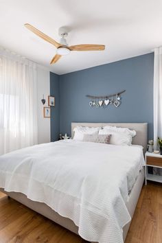 a bedroom with blue walls and white bedding