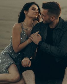 a man sitting next to a woman on the beach