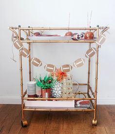 a gold bar cart with football decorations and plates on it, along with other items